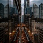 Urban cityscape of Chicago showcasing skyscraper reflections at dusk with busy streets and railway lines.